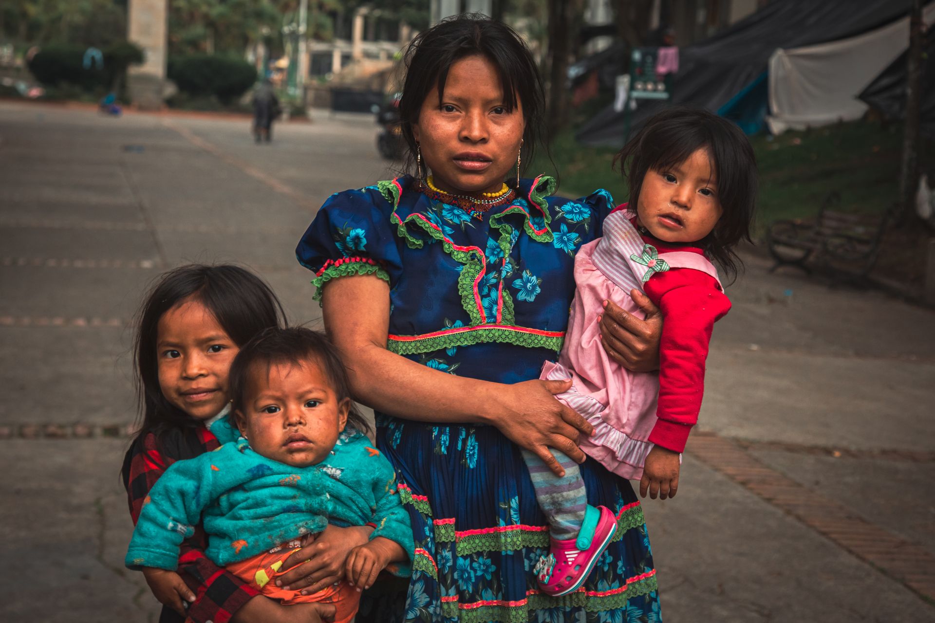 A mother with her children on a street in Bogotá, showcasing indigenous culture.