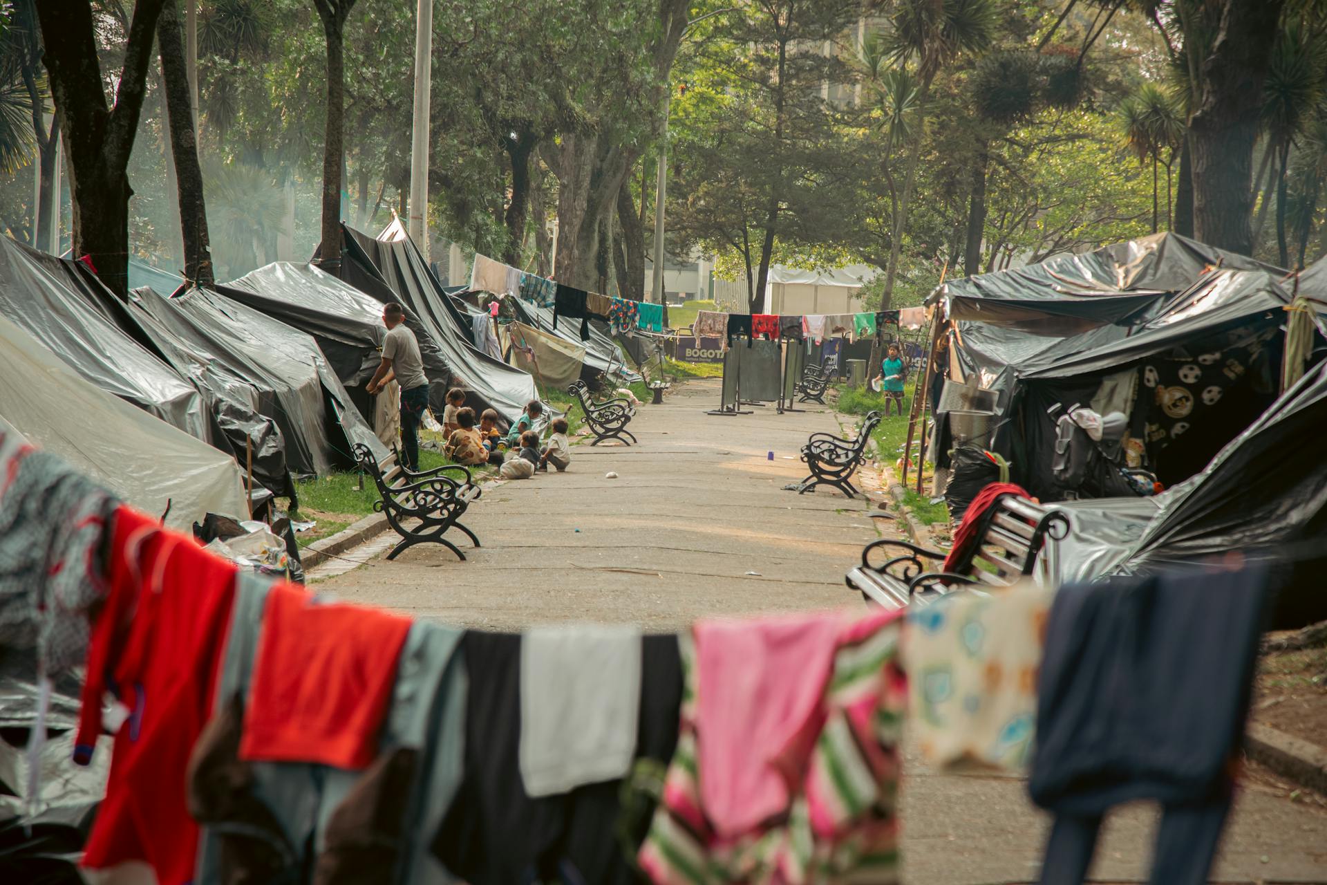 People camping in an urban park with tents and laundry in Bogotà, Colombia.