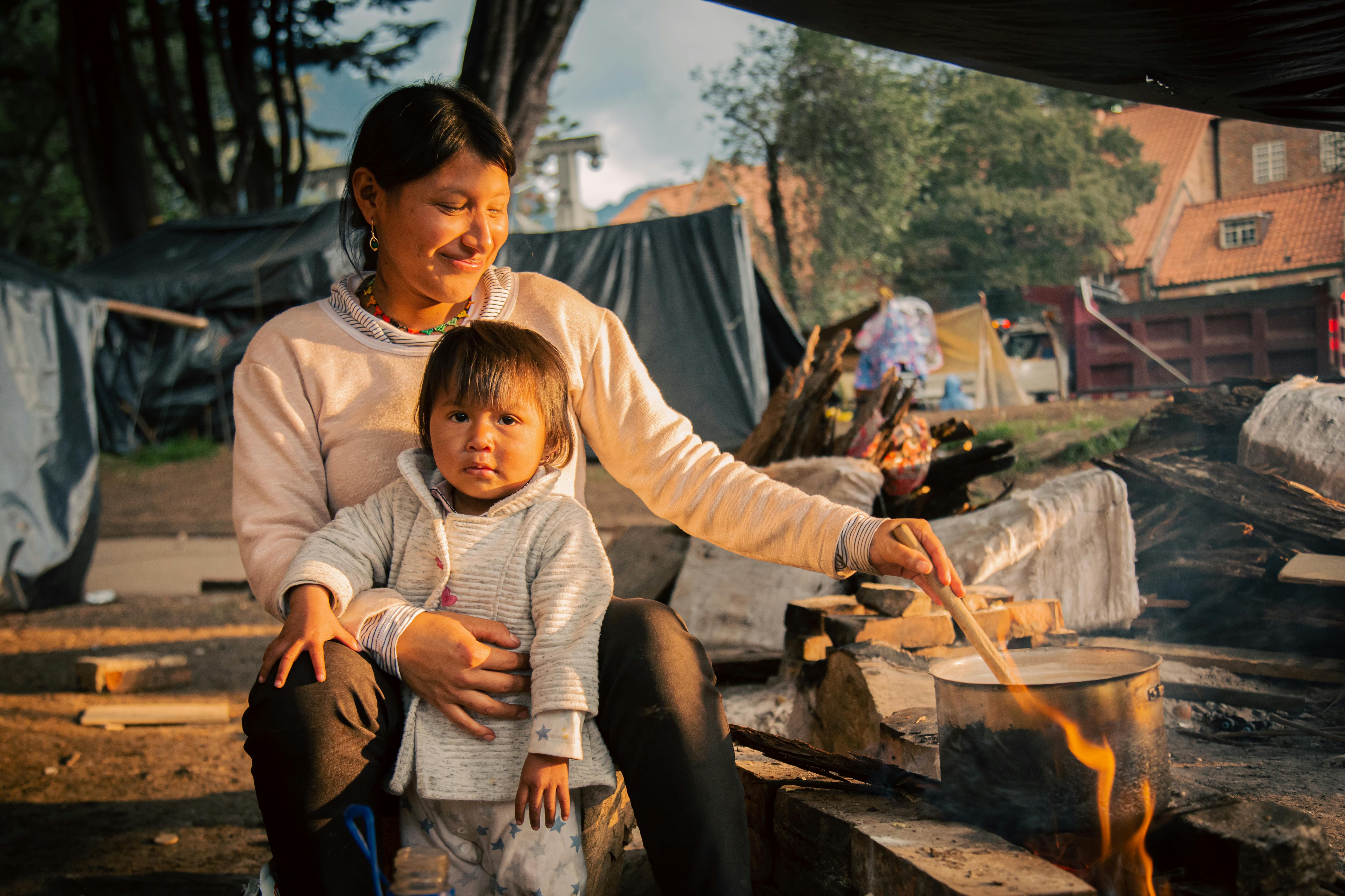 A mother cooking with her child in an outdoor setting in Bogota, Colombia, enjoying a warm familial moment.
