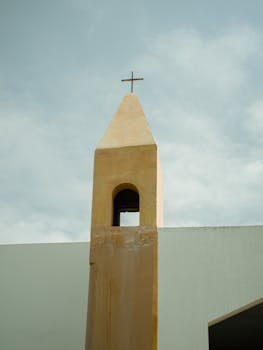 Golden bell tower with cross in Salvador, Brazil under a soft sky.
