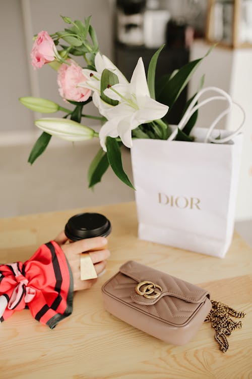 Hand with a Ring, Paper Cup, Handbag and Flowers in a Shopping Bag