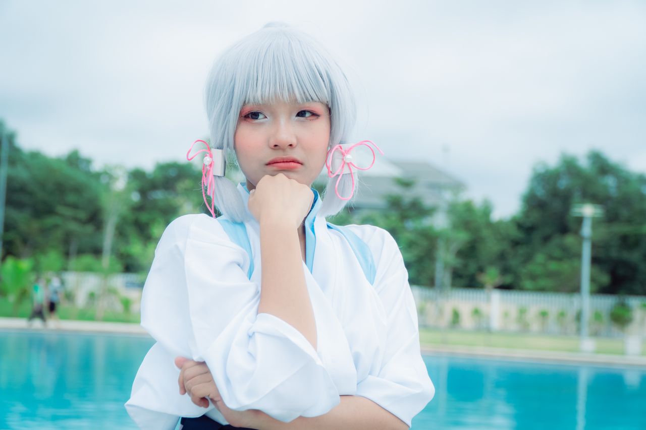 woman in cosplay with white hair posing thoughtfully near a pool