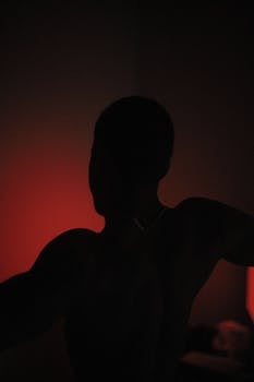 Mysterious silhouette of a person with red backlighting creating a dramatic effect.