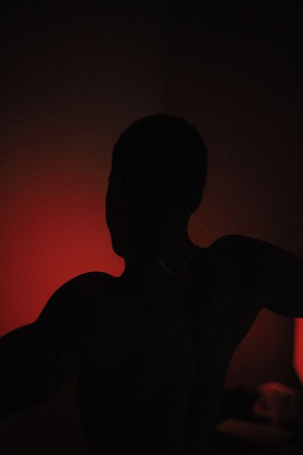 Mysterious silhouette of a person with red backlighting creating a dramatic effect.