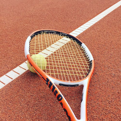 Orange and White Tennis Racket on the Ground 