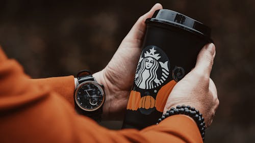 Close-Up Shot of a Person Holding a Black Starbuck Coffee Cup
