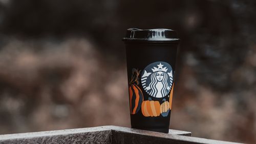 Free Reusable coffee cup with pumpkin design outdoors in autumn setting. Stock Photo