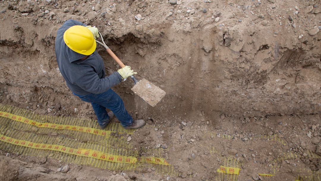 A worker digging a trench with a shovel, seen from above