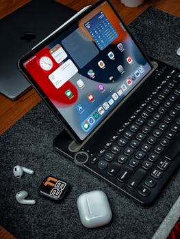 A sleek home office setup featuring a tablet with keyboard and wireless earbuds, perfect for work or study.