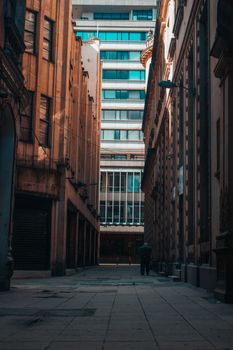 Explore a narrow alleyway lined with historic architecture in Bogotá during the day.