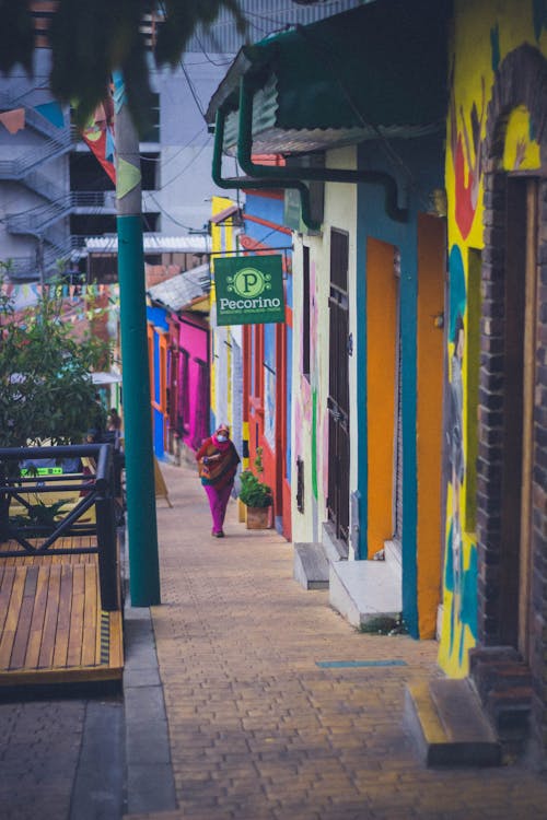 Woman Walking up Street of Colorful Houses