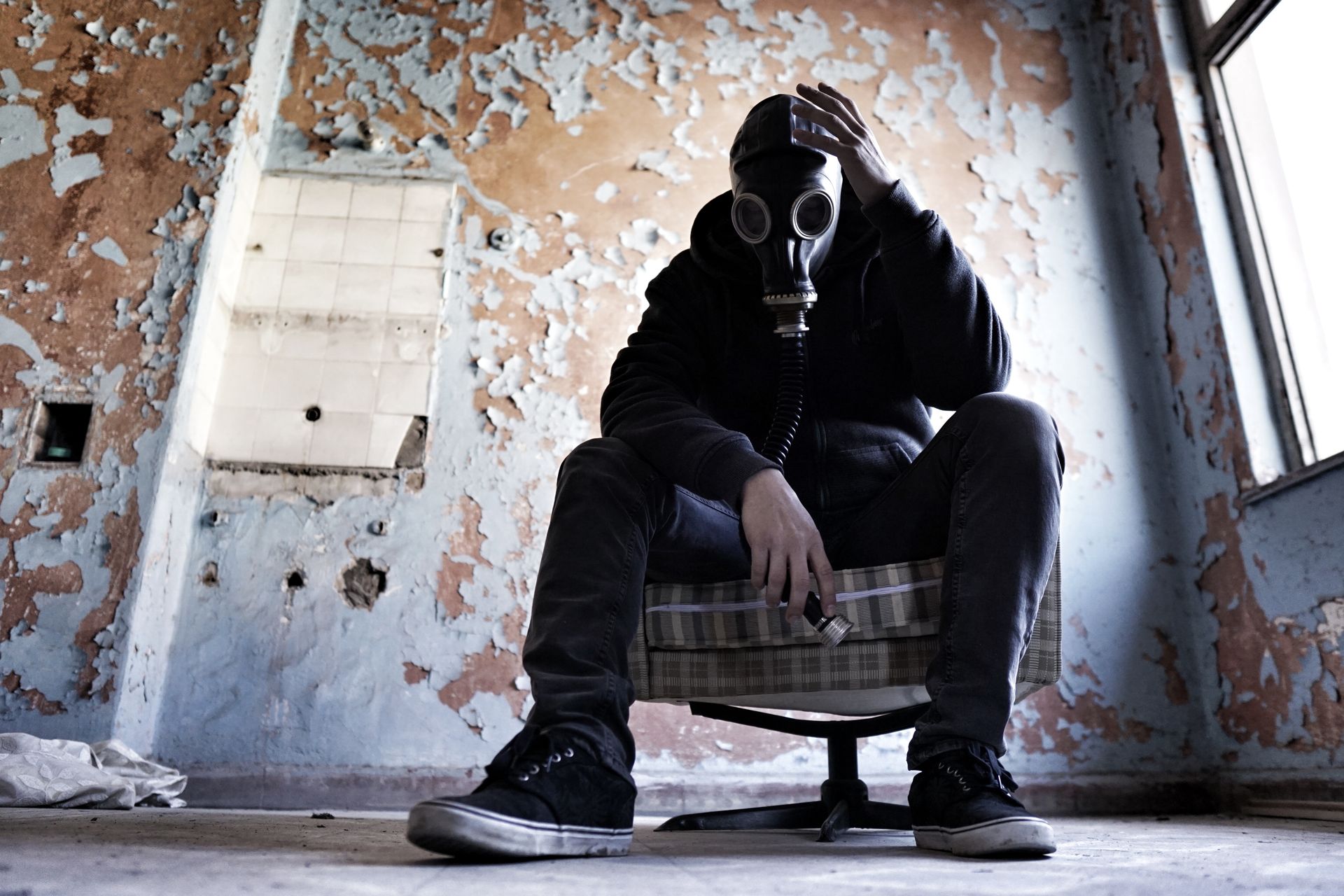 Man in a Gas Mask Sitting in an Abandoned Room