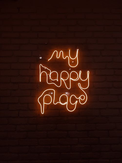 Free Glowing neon sign reading 'my happy place' mounted on a brick wall, creating a warm ambiance. Stock Photo