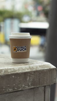 A takeout coffee cup from Donut Duck on a Milan street corner, emphasizing city life.