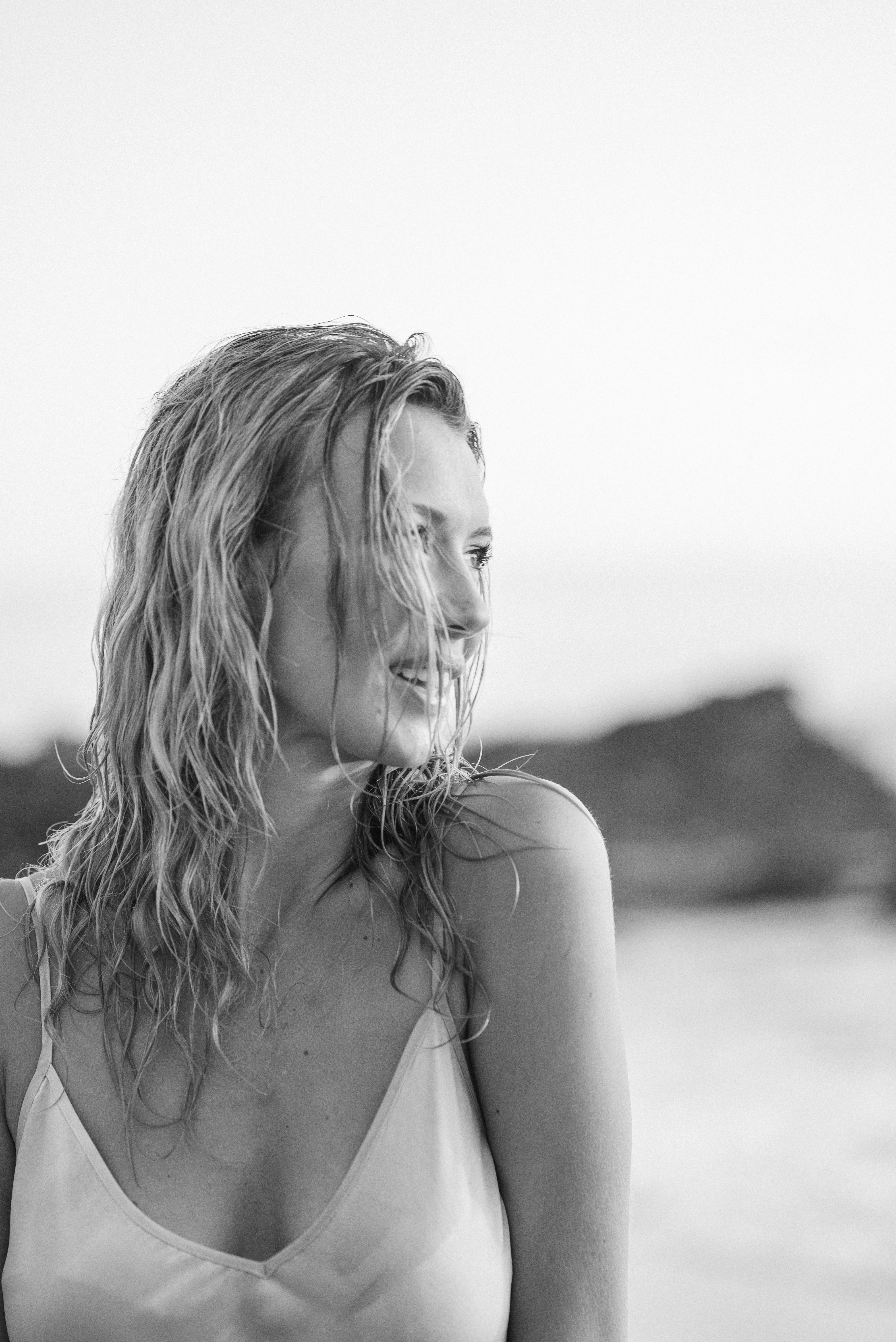 Monochrome portrait of a woman with wet hair smiling outdoors, evoking a serene mood.
