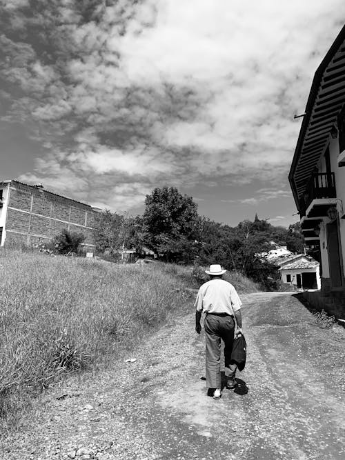 Back View of a Man Walking on a Road in the Countryside 