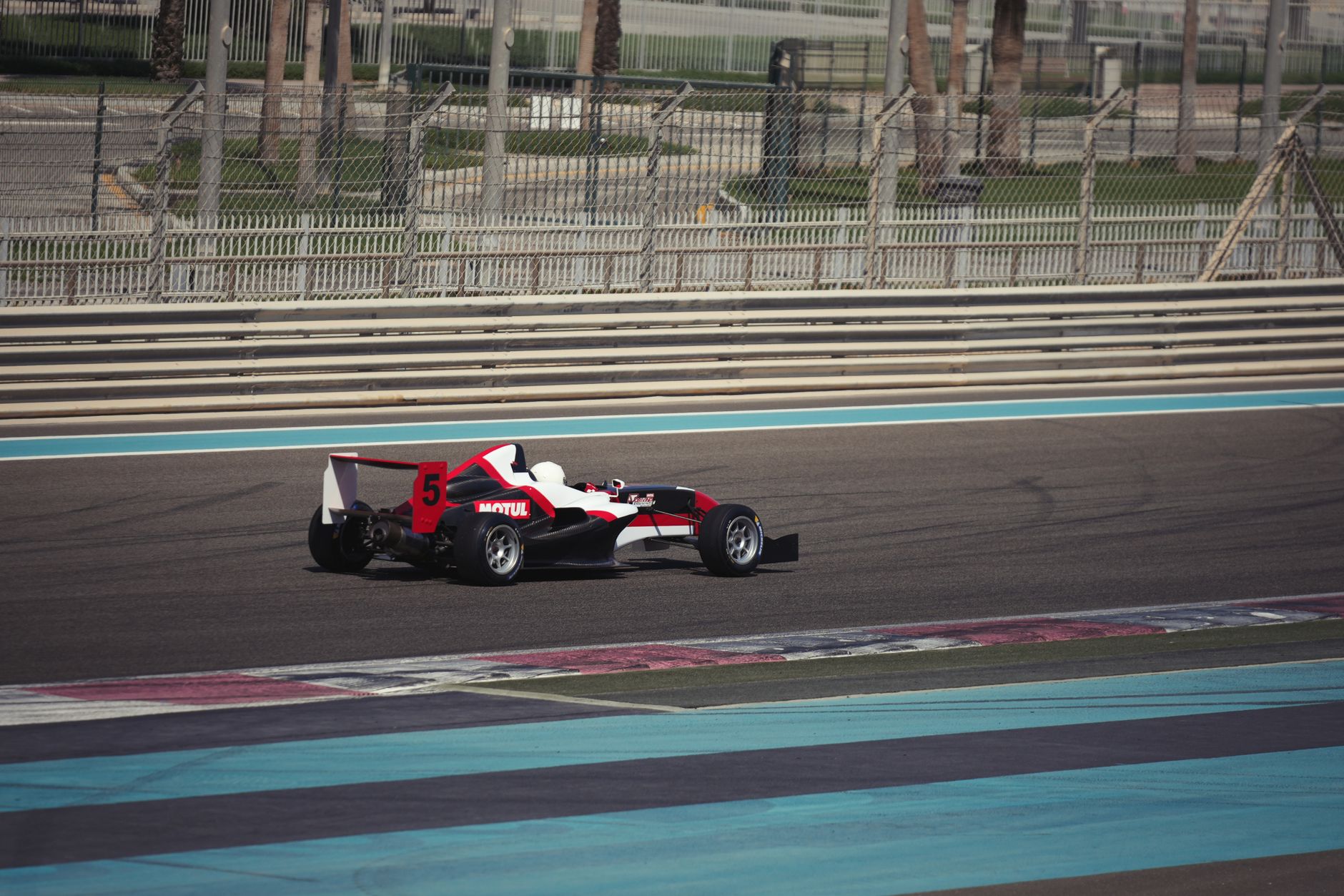 A sleek race car on Yas Marina Circuit in Abu Dhabi, showcasing speed and precision on a sunny day.