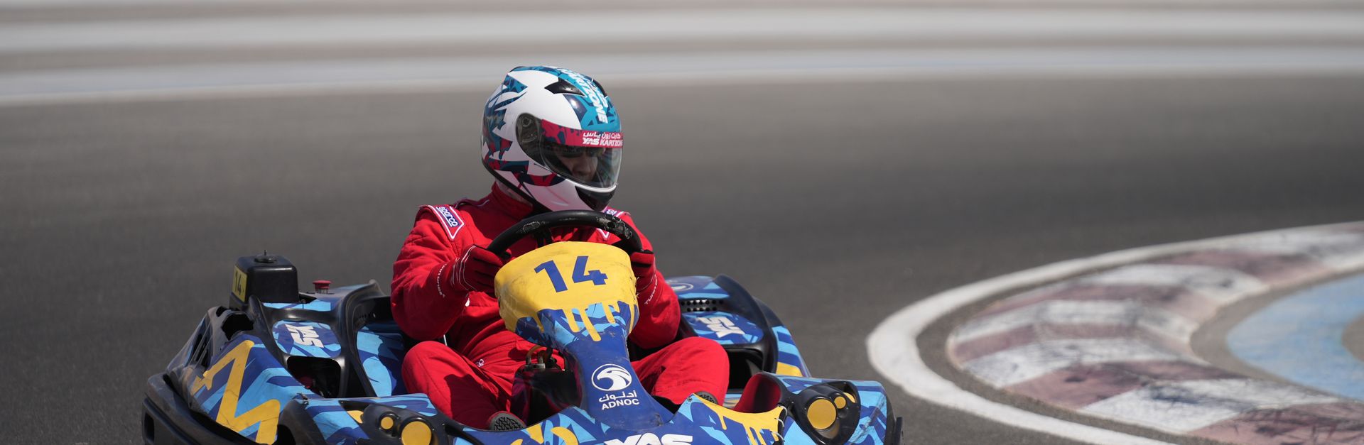 A go-kart racer in red suit speeds on Yas Marina Circuit in Abu Dhabi.