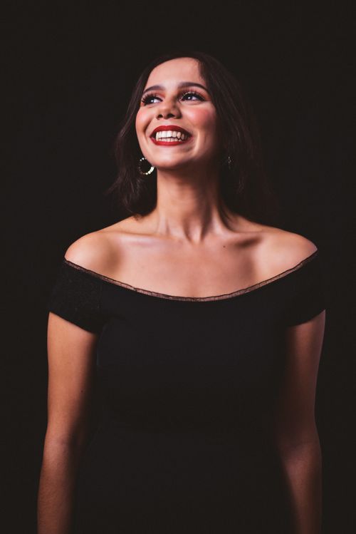Free Charming portrait of a woman in an off-shoulder top, smiling joyfully in a studio setting. Stock Photo