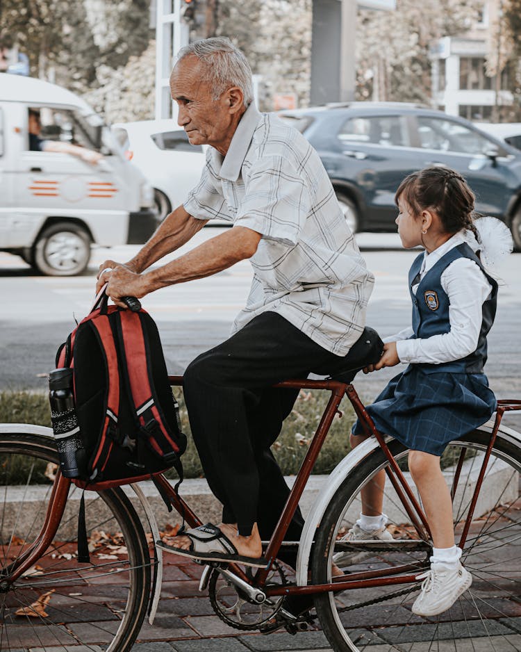 An Elderly Man And Young Girl Riding A Bicycle