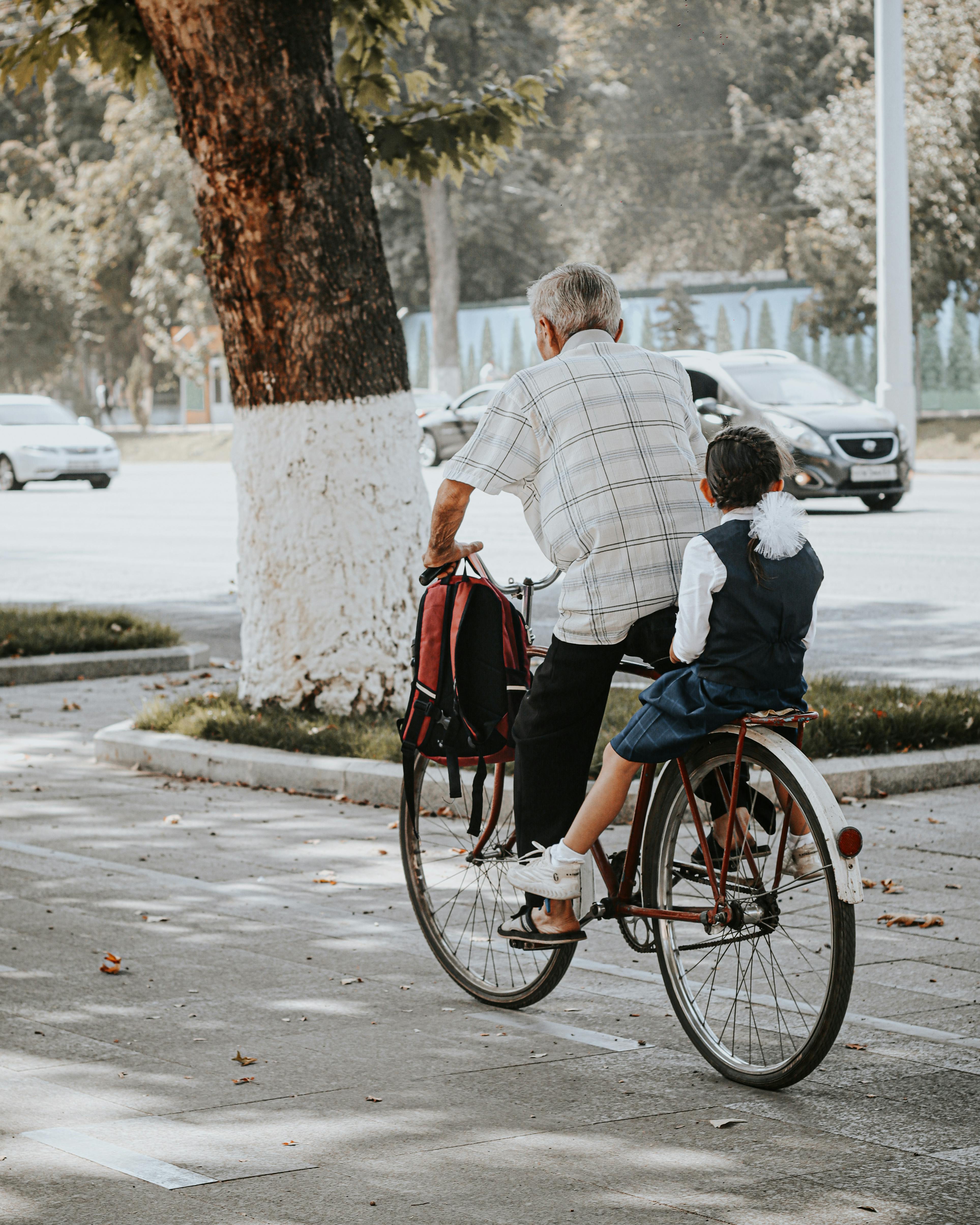 Old man and young girl riding a bicycle together on a sunny day, bonding moment.