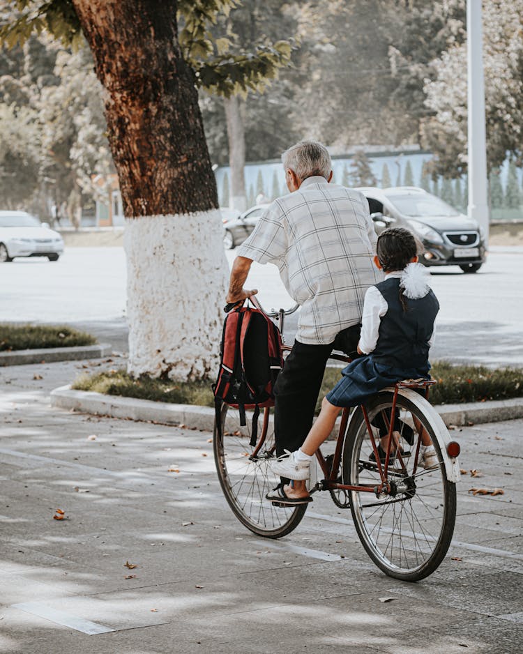 An Old Man And A Child Riding A Bike