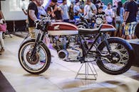 在室内公共自行车展上，一辆老式摩托车正在展出，周围聚集了不少人