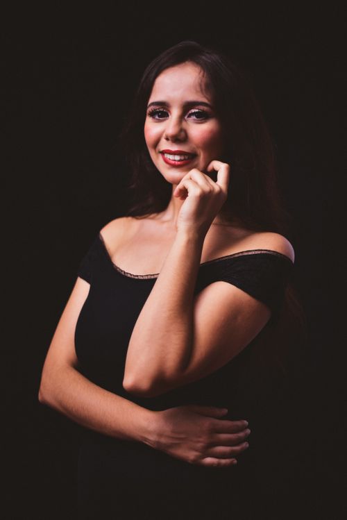 Free A stunning studio portrait of a smiling woman in an elegant black dress with red lips. Stock Photo