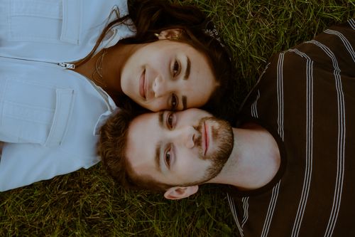 Free A loving couple lying on grass, close and content outdoors. Stock Photo