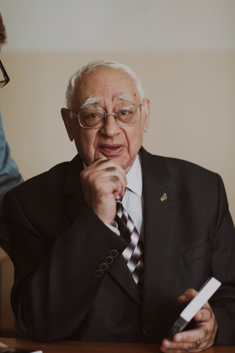 A Man In Black Suit Jacket Wearing Eyeglasses