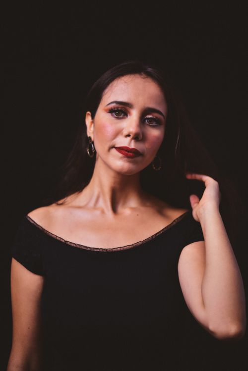 Free Glamorous portrait of a woman in a black dress with red lipstick set against a black background. Stock Photo