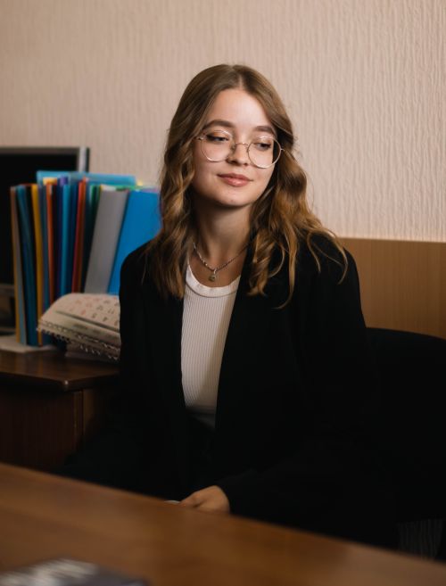 Free Stylish woman wearing a black blazer and eyeglasses, sitting indoors with colorful folders. Stock Photo