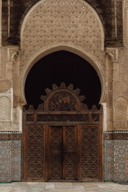 Beautiful intricately carved wooden doorway with detailed tile work in Morocco.