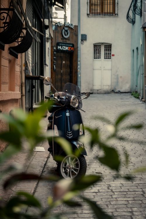 Free A Vespa scooter parked in a charming alley, creating a vintage urban vibe with mystery and nostalgia. Stock Photo