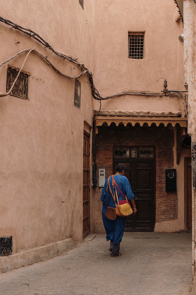 Person Walking On A Narrow Alley Carrying Leather Shoulder Bags