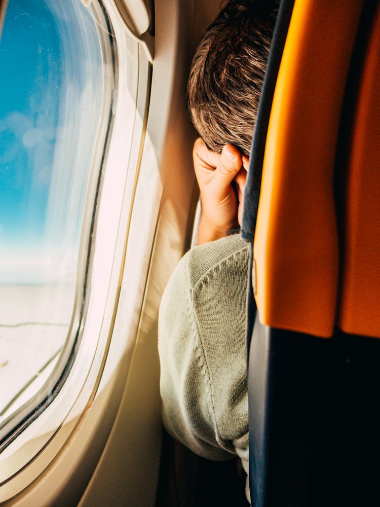 Back View Of A Man Sitting By The Window In An Airplane 