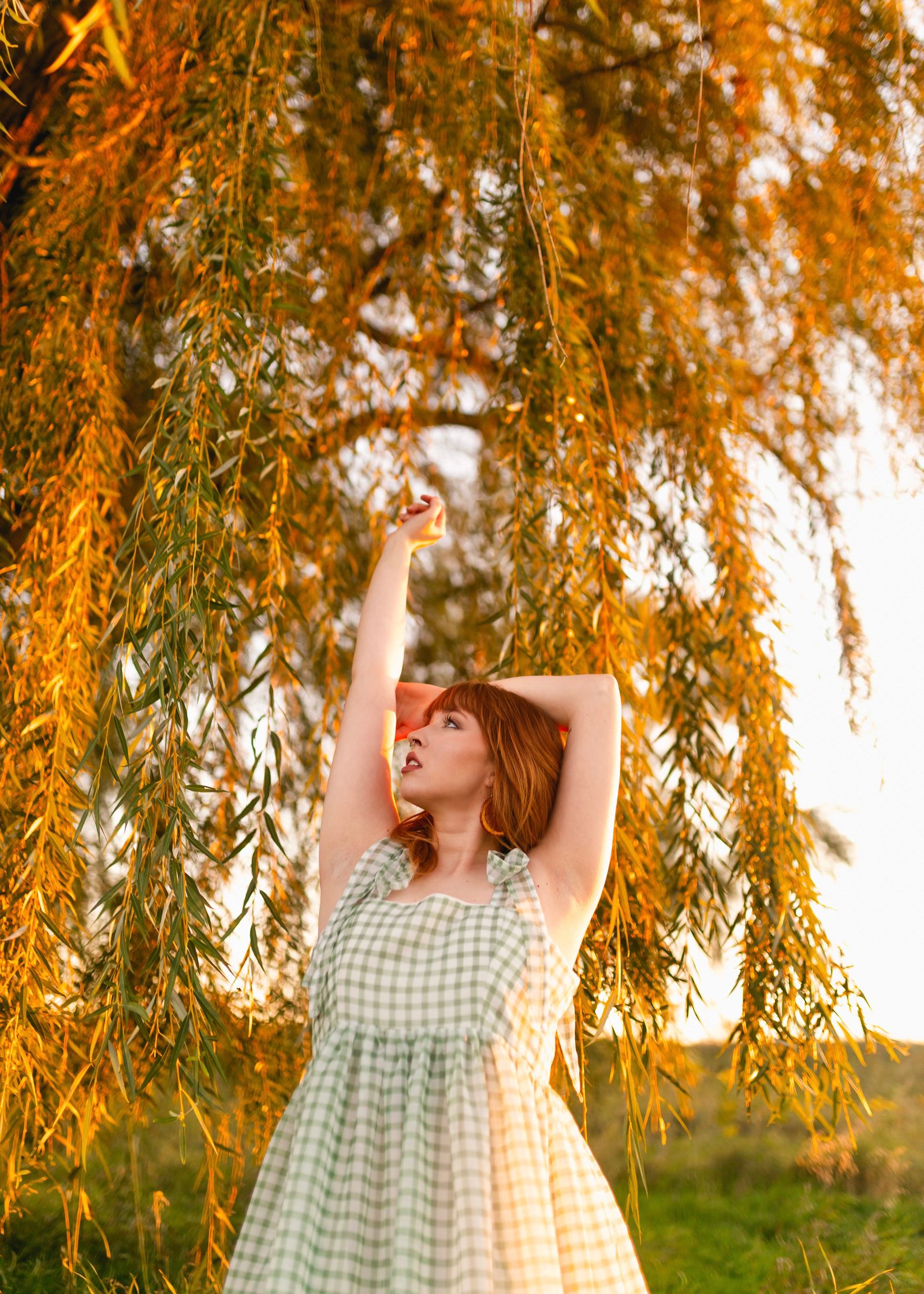 A woman in a white and green checkered sleeveless dress raising her hands