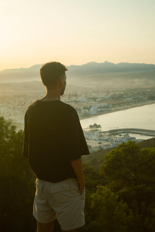 Back View of Man in Black Shirt Standing on Cliff