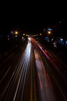 Long exposure shot of a busy road at night highlighting vibrant light trails and street lights.