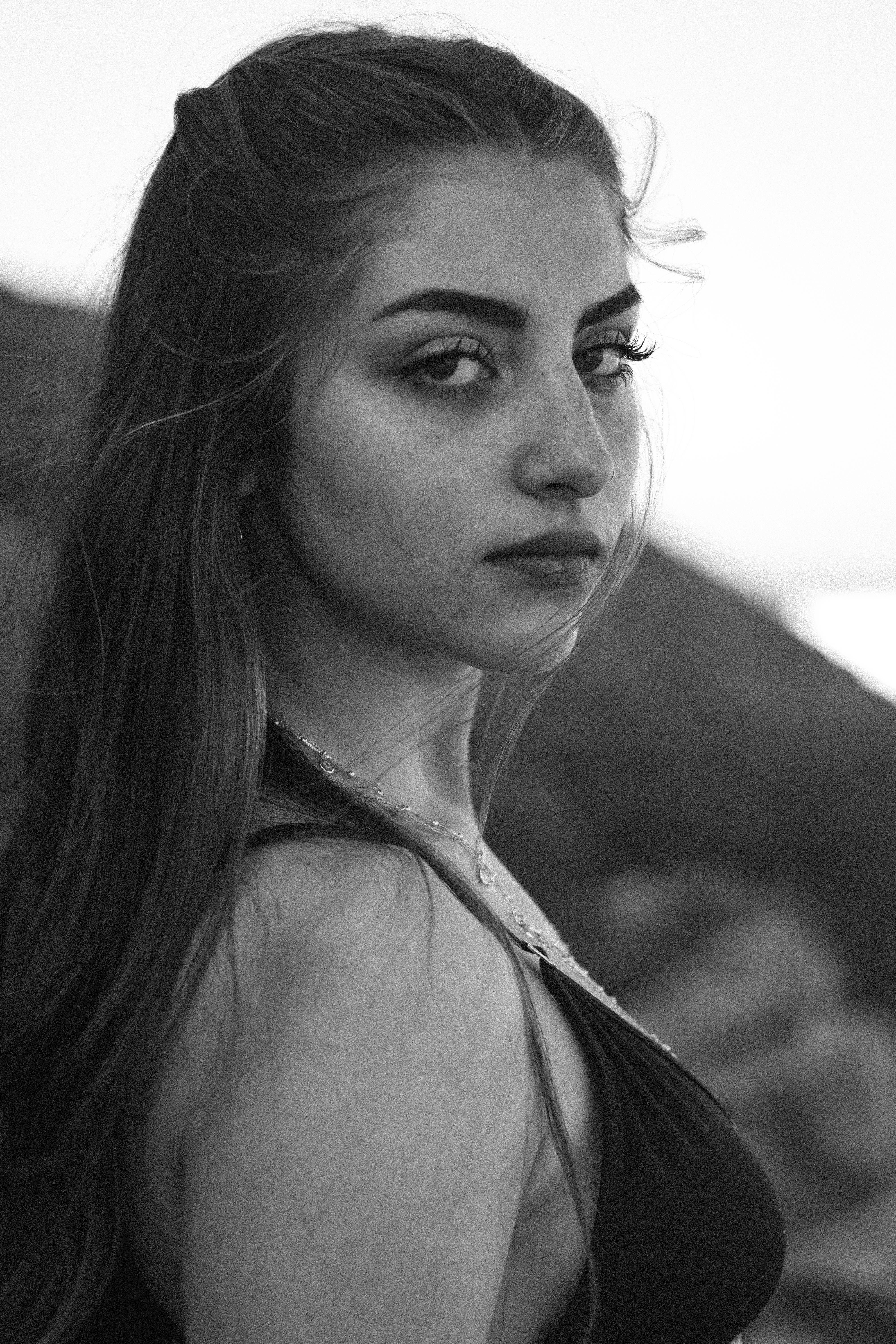 Black and white portrait of a young woman with long hair and freckles.