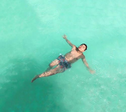 A Man in Blue Shorts Swimming in Water