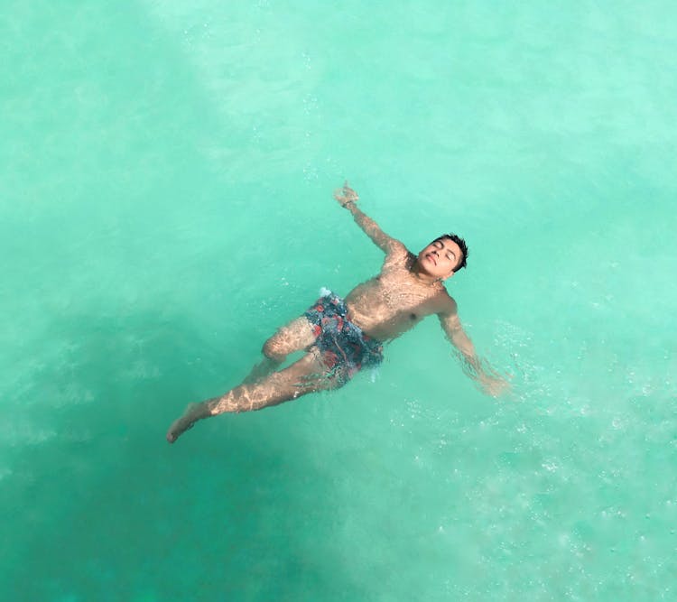 A Man In Blue Shorts Swimming In Water