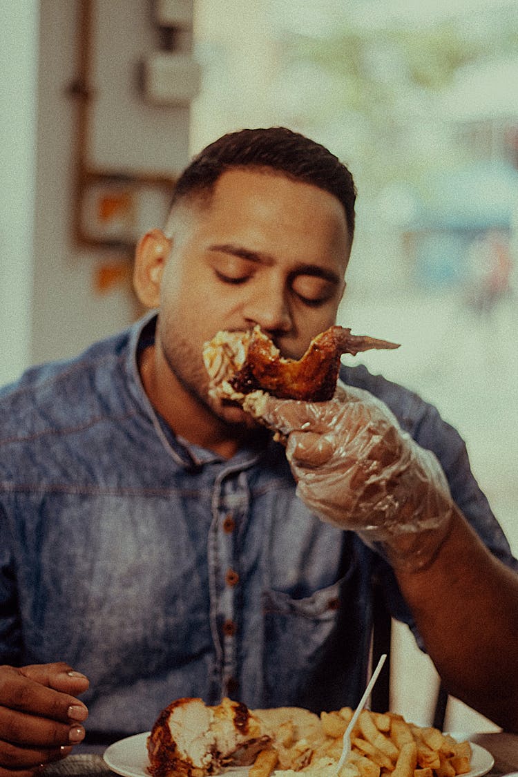 Man Eating Roasted Chicken While Wearing A Plastic Glove 