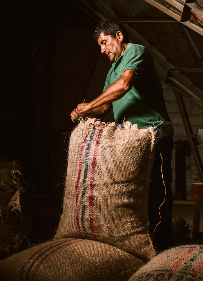 A jute bag of coffee being closed in a warehouse