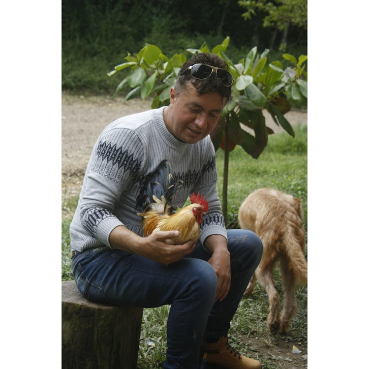 Man Wearing Sweater Holding A Chicken