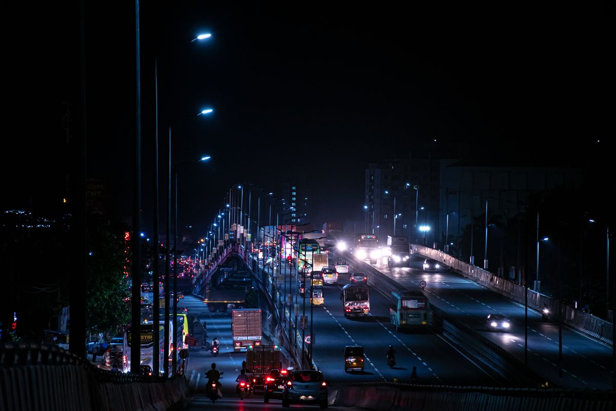 An Indian flyover at night with buses, autos and bikes
