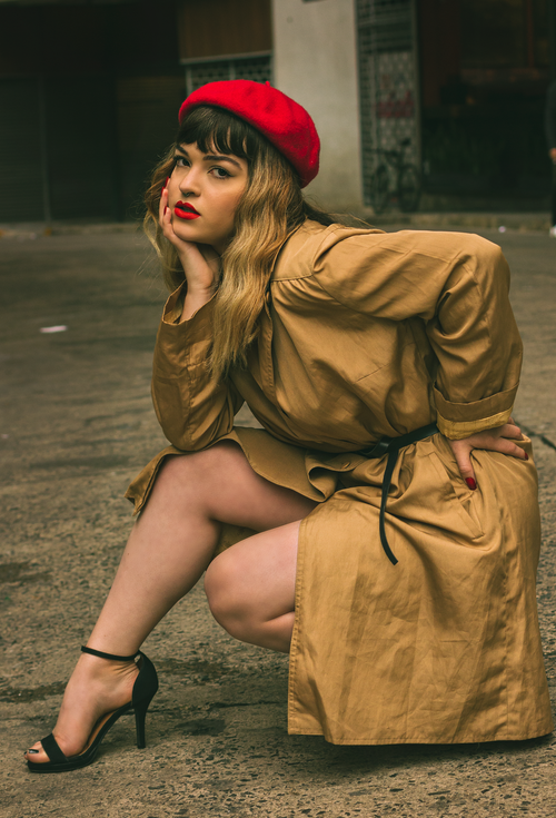 Free Fashionable woman in a trench coat and red beret striking a pose in an urban setting. Stock Photo