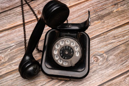 Close-up of a black vintage rotary phone on wooden background.