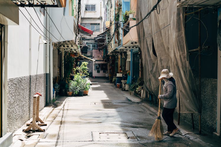 Person Sweeping A Street Between Buildings