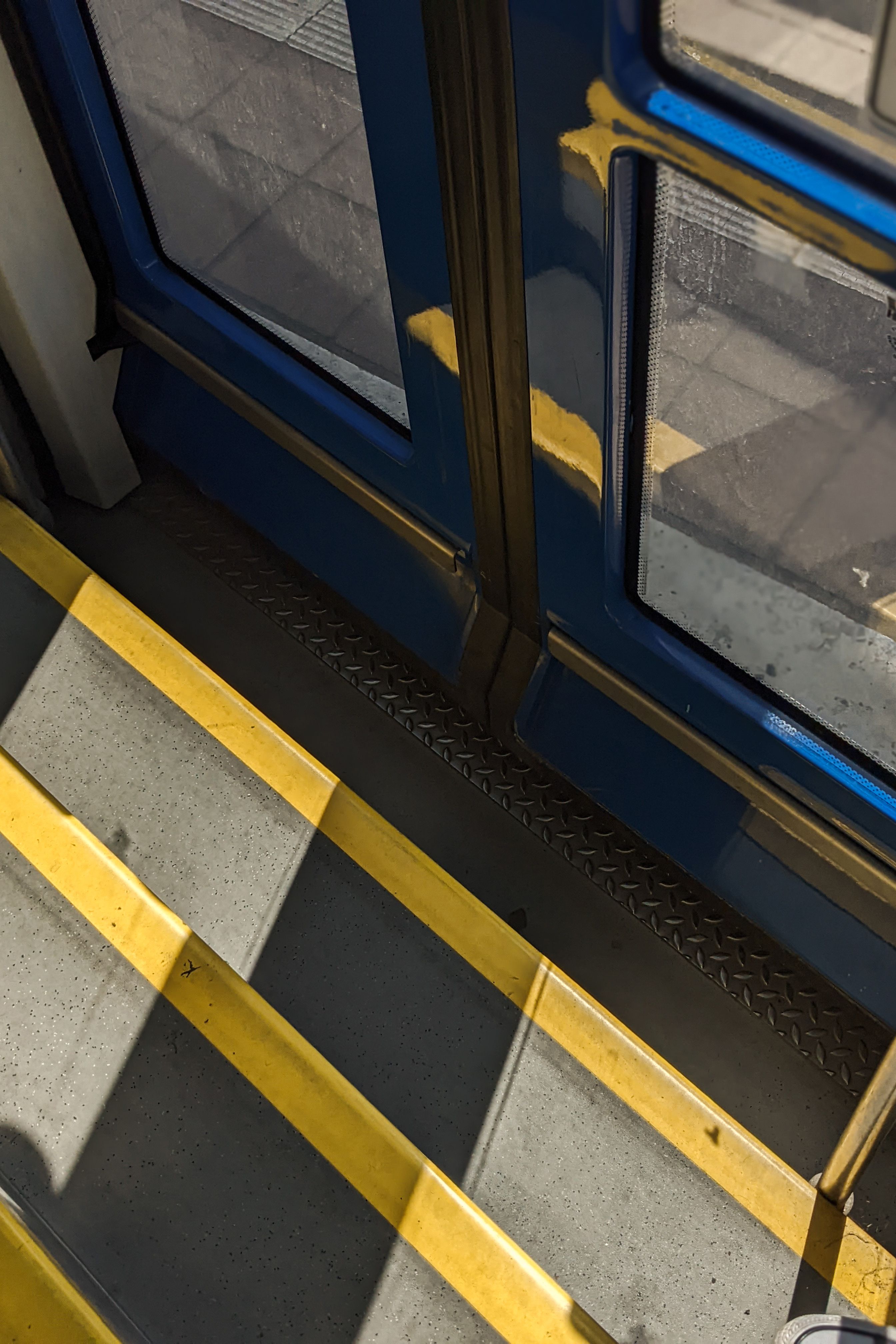 High angle view of bus steps with blue and yellow accents. Urban transportation concept.